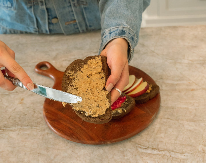 Hands spreading nut butter onto a slice of toast