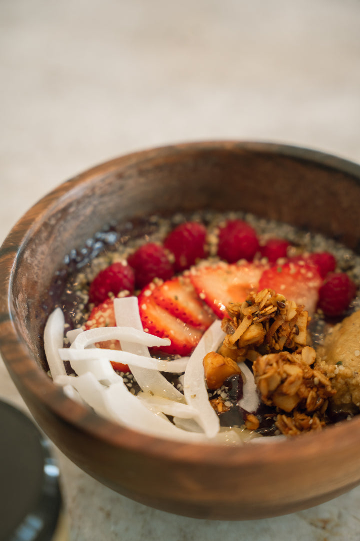 A breakfast bowl topped with nut butter, berries, and coconut