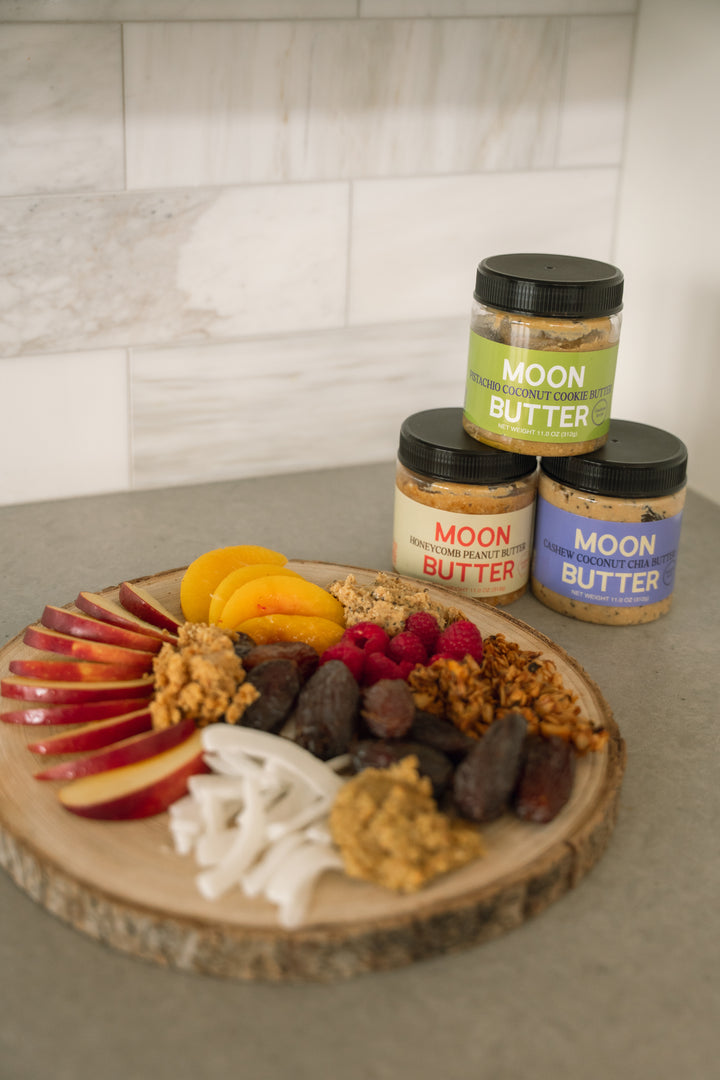 Apple slices and fresh fruit served beside MoonButter jars