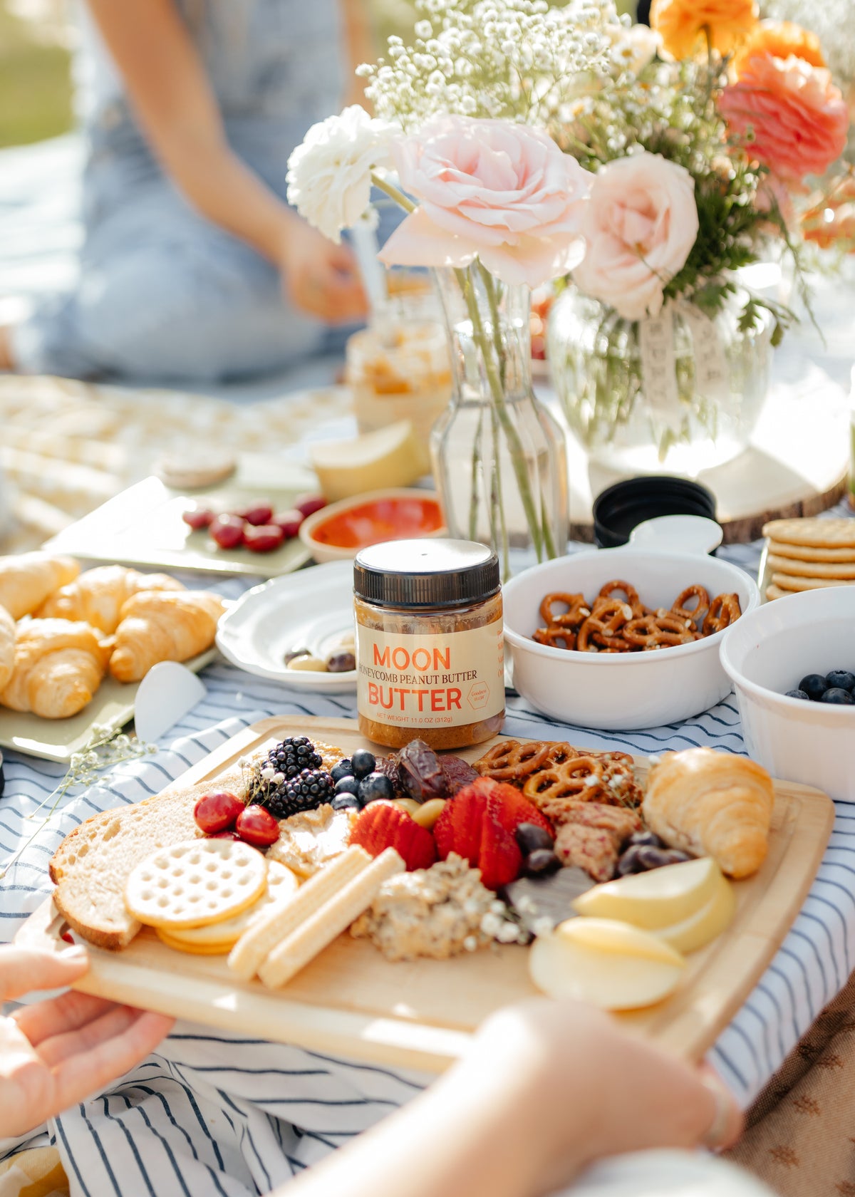 Moon Butter Honeycomb Peanut Butter on a brunch table with fruit, crackers, pastries, and flowers